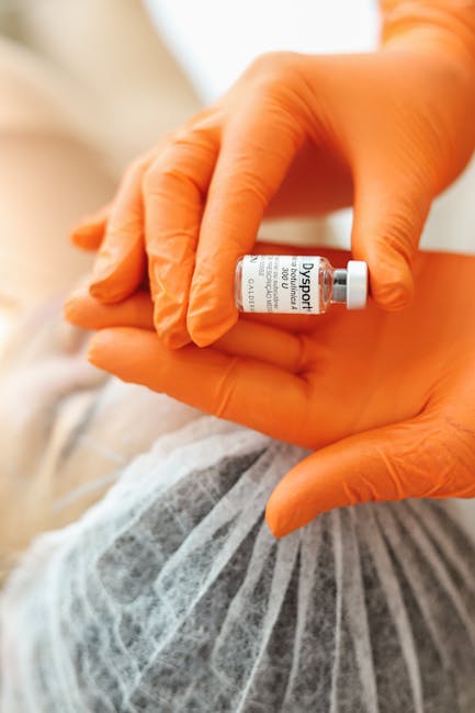 Orange-gloved hands holding a small Dysport vial in a healthcare setting.