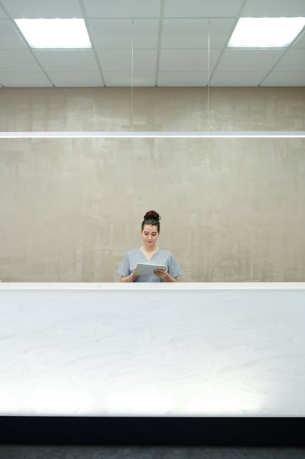 A professional receptionist at a sleek modern front desk, focused on her work.